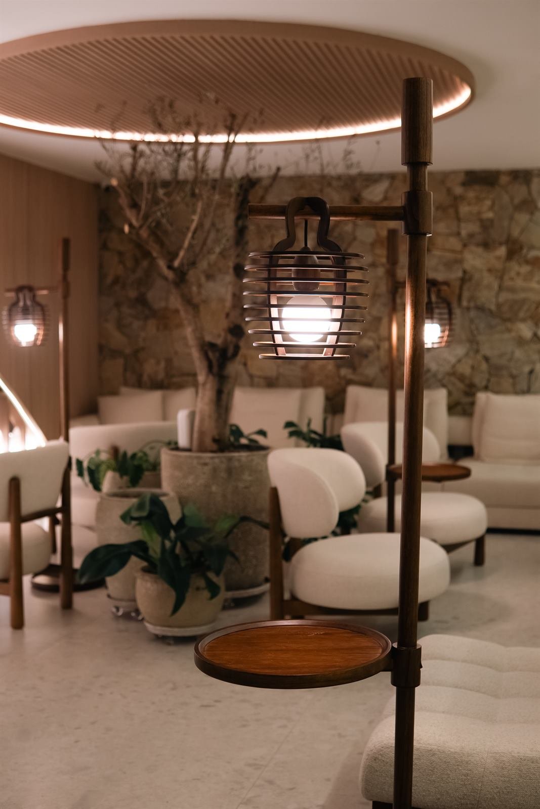 Lounge do Espaço Infinitta com luminária, parede de pedra e plantas